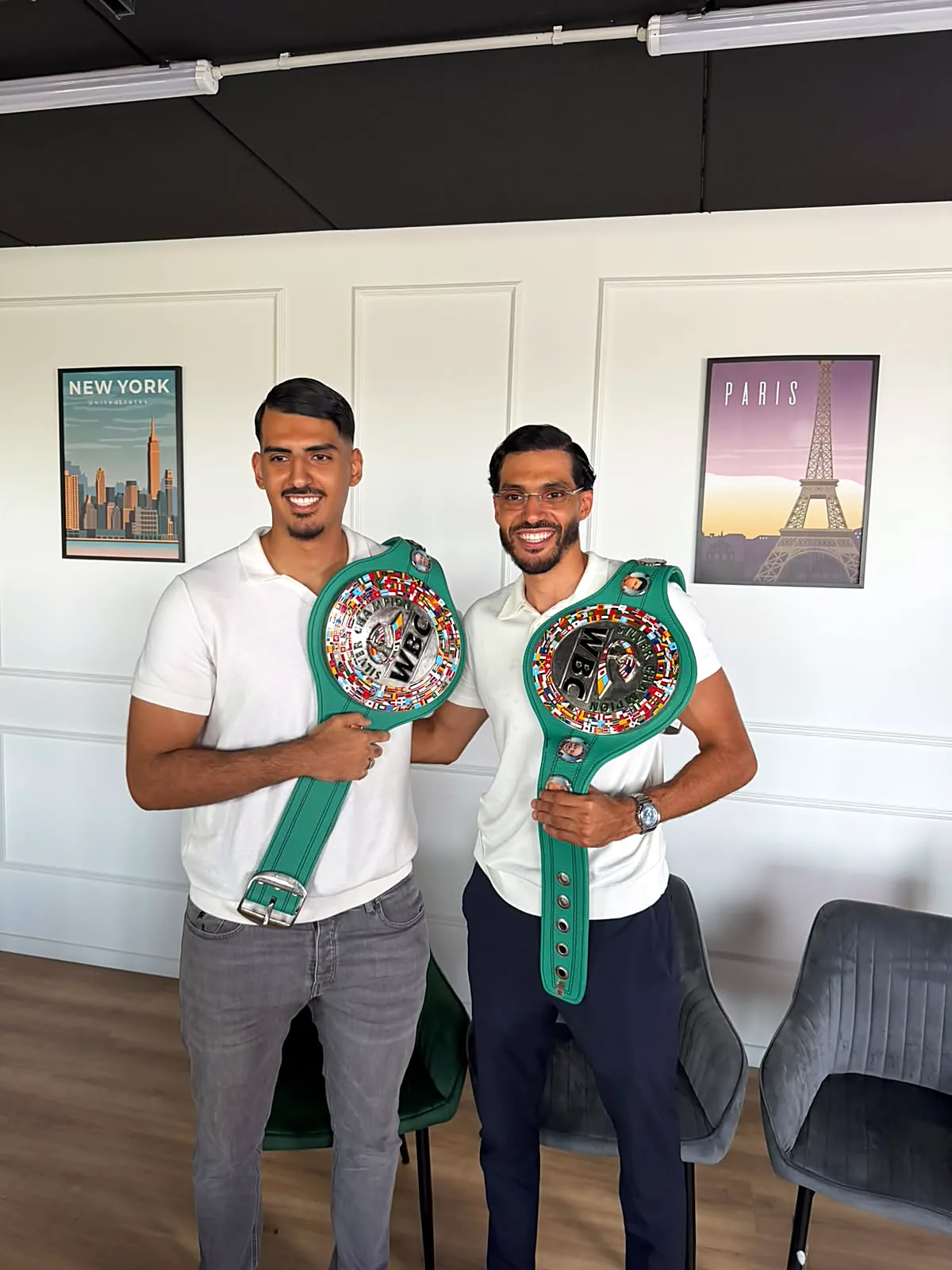 Deux champions posent avec leurs ceintures dans la salle de l'école